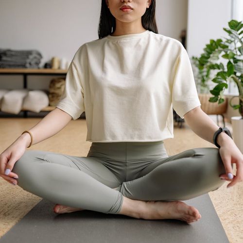 Child sitting quietly on a yoga mat with eyes closed, looking focused and calm.